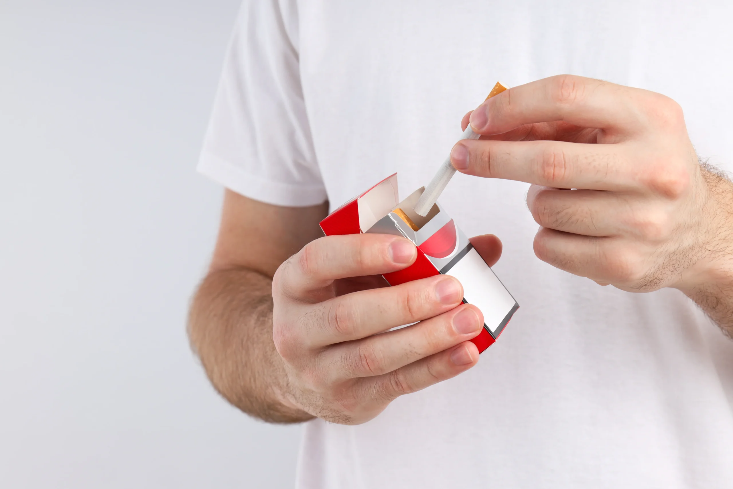 Pessoa retirando cigarro de um maço, ilustrando matéria sobre tributação fixa, preço tabelado e decisão do STJ sobre PIS/Cofins aplicados ao setor de cigarros.